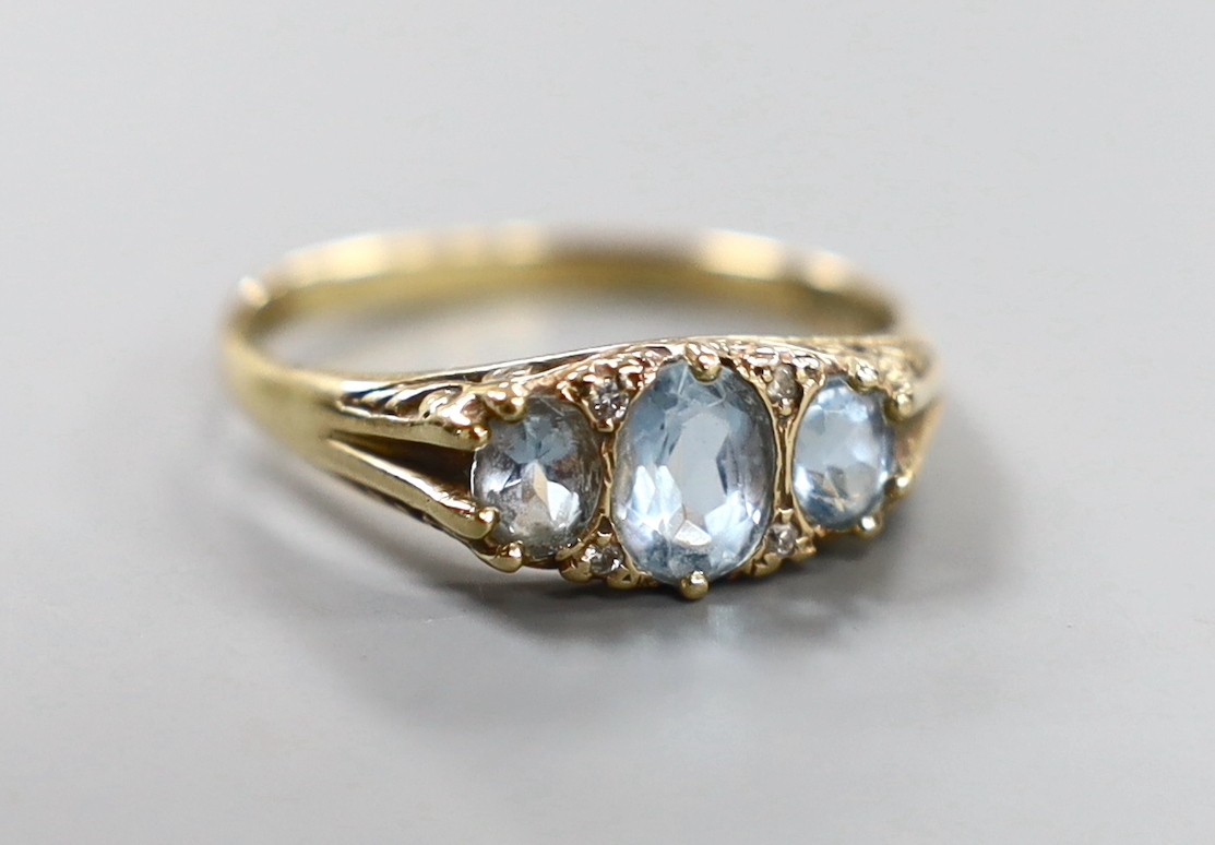 A modern 9ct gold, three stone blue topaz and diamond chip set ring, size W, gross weight 3.8 grams.